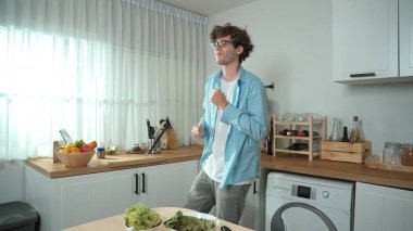 Mutlu baba yemek pişirirken müziğe geçiyor ve modern mutfakta öğle yemeği hazırlıyor. Aktif baba, sebze ve mutfak gereçleri ile çevrili sağlıklı yemek ya da salata yaparken şarkıyla dans ediyor. Pedagoji.