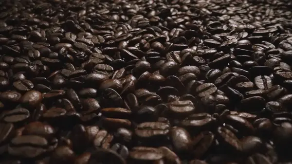 stock image Macro shot of super slow motion shot of fresh coffee bean placed with black background. Close up of piles of aromatic roasted coffee seed surrounded. Macrography. Beans scattering around. Comestible.