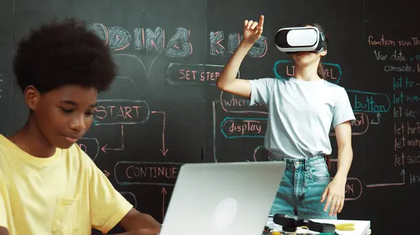 stock image Smart african student programing and coding innovative system while caucasian girl enter in metaverse or virtual world by using VR or head set at blackboard in STEM technology classroom. Edification.