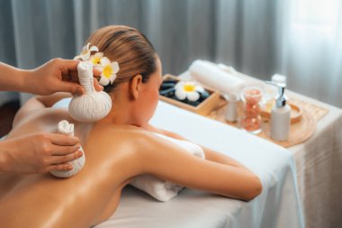 Sıcak bitkisel top spa masaj vücut tedavisi, masör kadın vücuduna nazikçe şifalı bitki torbası bastırıyor. Aromaterapi dinlenme sükuneti ve sükuneti kaplıca salonundaki atmosferi aydınlatıyor. Sessiz.