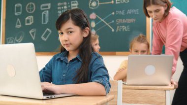 Akıllı Asyalı kız, mühendislik komut yazarken kameraya bakıyor. Çok kültürlü bir öğrenci yapay zekayı öğrenirken öğretmenler sistemi öğretiyor ya da STEM sınıfında sınıfları kontrol ediyor. Pedagoji.