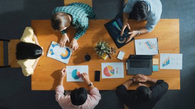 Proje yöneticisinin veri ve mali tabloyu analiz etmek için tablet kullanırken pazarlama ekibinin pazarlama kampanyası ya da toplantı odasında planlama stratejisi üzerinde birlikte çalışmasının en üst görüşü. Cemaat.