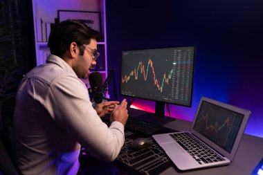 Akıllı tüccar işadamı, karanlık oda gecesinde neon ışıklı ofisteki arama pazarında yüksek kârla ekranda bilgisayar ve bilgisayar üzerinde dinamik borsa yatırımları üzerinde yoğunlaşıyor. Tahmin et..