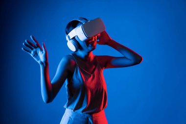 Zeki bir kadın, metaevreni birbirine bağlayan VR kulaklık takan neon ışıklarla çevrili duruyor. Gelecekteki siber uzay topluluğu teknolojisi. Zarif bir kadın dans etmekten, dans etmekten ve şarkı söylemekten hoşlanır. Halüsinasyon.