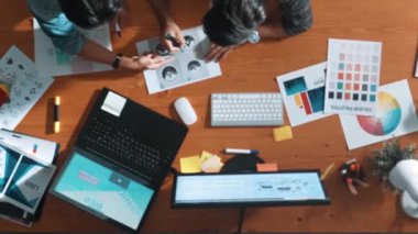 Takım ayakta dikilirken ve yorum yaparken müdürün fikir yazma konusunda üst düzey görüşü. Profesyonel tasarımcı logosu renk paletine bakarken ve renkli kalemle fikri kağıda yazarken. Sempozyum.