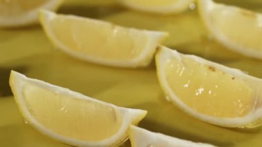 Sarı arka planda suya düşen limon dilimlerinin yukarıdan görünüşü. Taze limon dilimlenmiş, ayrı sarı arka planda su dökülüp sıçrama yapılan yere yakın durun. Citrus tazeliği. Pabulum.
