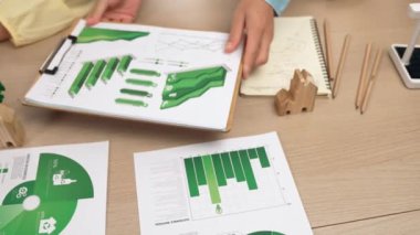 Şirketin gelecekteki EG 'si için yeşil enerji grafiği kullanımına danışmanlık ve analiz yapan iş ekibi. Yel değirmeni modeli, masadaki temiz enerji ve ev bloğu sembolize edilmiş eko evi kullanarak temsil ediliyor. Tanımlama.