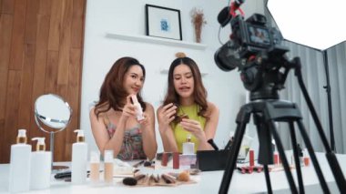 İki kadın nüfuzlu partner sosyal medya veya blog için canlı yayın yapan video klip inceleme derisi çekiyorlar. Canlı kozmetik stüdyo ışığı olan genç bir kız çevrimiçi pazarlama kayıt oturumu yayını için.