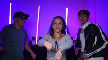 Çok kültürlü break dans takımı mor neon ışıkla stüdyoda müzik yapıyor. Stüdyoda farklı arkadaşlara bakarken serbest dans eden enerjik sokak dansçıları grubu. Çılgınca. Mutluluk.