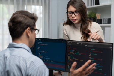Masada çalışan erkek programcının karşısında duran kadın meslektaşım iki bilgisayar ekranında kodlama web sitesi yazılım sistemi projesini tartışmak için tam yığın veri dizaynı ile karşılaştırıyor. Varsayım.