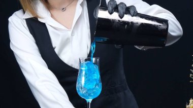 Makrografi, maharetli bir barmenin sanatını tecrübe edin. Mavi Hawaii kokteylini çarpıcı bir siyah arka plana ustalıkla dökerken. Kokteyl. Yakın plan çekim. Geliştirilebilir.