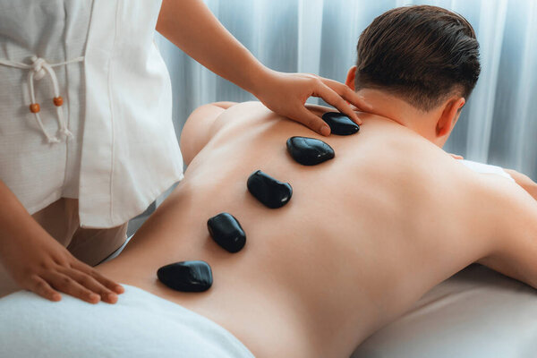 Массаж горячими камнями в спа-салоне на роскошном курорте с дневной легкой атмосферой спокойствия, блаженный клиент, наслаждающийся спа-массажем из базальтового камня скользит по телу с успокаивающим теплом. Quiescent