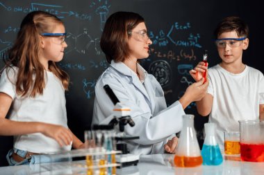 Laboratuvarda çalışan öğretmen, güvenlik gözlüğü takıyor, STEM sınıfında kimya bilimi üzerine deney yapıyor. Öğrenci komedisi tüpte sıvı deneyi yapar. Etkinlik.