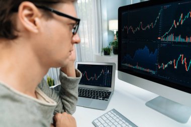 Bilgisayar ve dizüstü bilgisayarı kullanarak, çalışma masasındaki dinamik artırılmış borsa grafiğinin en yüksek kar değerini araştıran bir tüccar, modern ofisteki ekrandaki döviz kuru değerini analiz ediyor. Bireysel.