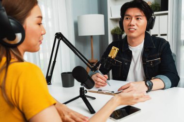 Gülümseyen radyo etkili sunucusu kulaklık takıyor kadın konuşmacı ile röportaj yapıyor sosyal medya internet sitesinden dinleyicilere bilgi paylaşıyor stüdyo kaydında sabah canlı yayın kanalı. İnfobahn.