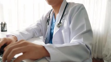 Hastanedeki doktor masasında oturup dizüstü bilgisayar üzerinde çalışıyor. Hasta test sonuçlarını teşhis ediyor, hastalıklar ve hastalıklar için tedavi planı geliştiriyor. Sağlık personeli ve sağlık hizmetleri. Ağır çekim. Katı.