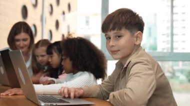 Çocuk BTMM Teknoloji dersinde çok kültürlü bir arkadaşıyla kameraya bakıyor. Mühendislik kodları ve bulanık geçmişi olan programlama sistemi üzerine çok kültürlü bir öğrenci çalışması. Etkinlik.