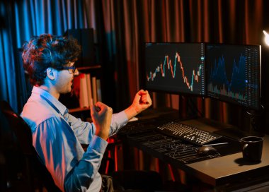 Başarılı bir tüccar, en yüksek karla yumruğunu kaldırıyor ve neon ışıklı modern ofiste gerçek zamanlı olarak küresel piyasaya bakıyor. Genç iş adamlarının dinamik borsa kavramı. Toplayıcı.