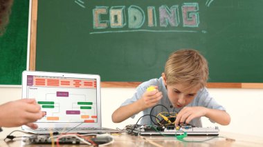 Kafkas akıllı çocuk kök teknoloji dersinde tornavida kullanarak ana tahtayı tamir ederken aynı zamanda gülümseyen öğrenci de dizüstü bilgisayar ekranı kodlu elektronik makineyi incelemek için birlikte çalışıyor. Pedagoji.
