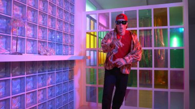 Komik break dansçı kameraya bakarken hiphop 'a doğru serbest adım atıyor. Çılgın mutlu hipster dans edip sokak dansı yaparken Led ışığında günlük kıyafet ve güneş gözlüğü takıyor. Mutluluk.