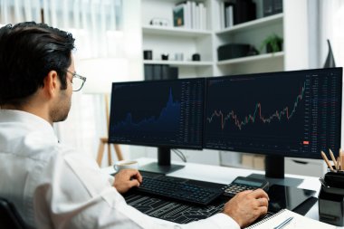 Akıllı tüccar işadamı, modern merkez ofisindeki araştırma pazarında en yüksek kârlı finansal teknolojiye yatırım yaparak bilgisayar üzerinde iki dinamik borsa yatırım ekranını analiz ediyor. Tahmin et..