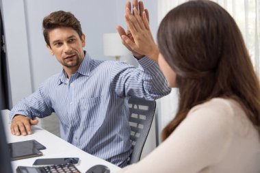 Gülümseyen mutlu iş arkadaşları beşlik çakıyor aynı zamanda yaratıcı proje planını yumrukluyor ve sabahları modern ofiste gündelik işlerde en yüksek kârı elde ediyorlar. Varsayım.