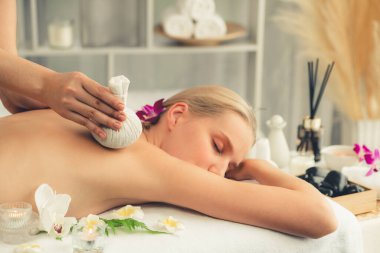Sıcak bitkisel top spa masaj vücut tedavisi, masör kadın vücuduna nazikçe şifalı bitki torbası bastırıyor. Aromaterapi dinlenme sükuneti ve sükuneti kaplıca salonundaki atmosferi aydınlatıyor. Sessiz.