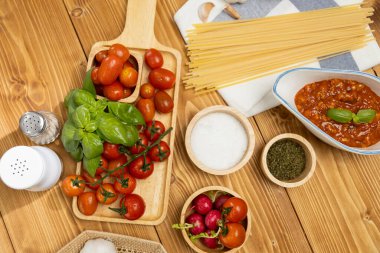 Lezzetli yiyeceklerin üst görüntüsü ev yapımı spagetti hazırlama masası kıymalı domates sosu ve fesleğen fırlatma unsurları şef masa dekorasyonu ile servis ediliyor. Varsayım.