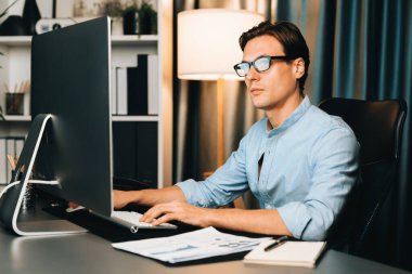 Akıllı iş adamı iş paragrafı dinamik pazarlama analizi planını analiz ediyor. Kağıt kağıtları ve bilgisayar monitörü raporlarını gece evdeki belge verileriyle karşılaştırmak için hazırlıyor. Bireysel.