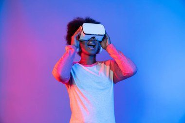 Profil, VR gözlük takan genç ve güzel Afrikalıların mavi ve pembe neon ışıklı arkaplanda izole olduğunu düşünüyor. Teknoloji ve dijital yenilik 3 boyutlu hologram gramında. Entrika.