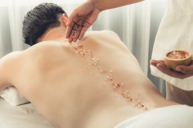 Lüks spa salonunda sıcak mum ışığı atmosferi olan lüks kaplıcalarda deri dökme tedavisi gören mutlu bir adam. Sağlık kaplıcasında güzellik tedavisiyle tuz temizliği. Sessiz.