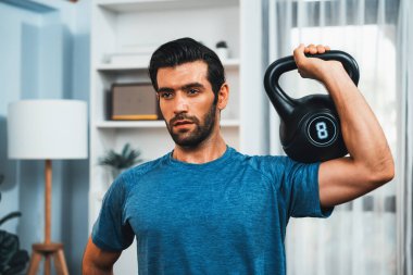 Atletik vücut ve aktif sporcu, sağlıklı vücut çalışma yaşam biçimi konsepti olarak eğlence evinde kas kazancı için kettlebell ağırlığını kaldırıyor..