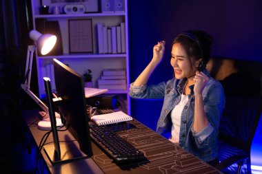 Sunucu kanalı Asyalı etkileyicisi canlı yayında konuşuyor. Sosyal medyada kulaklık takıyor, bilgisayar kaydı yapıyor, dinleyicileri selamlıyor ve Neon Modern Stüdyoları 'nda online olarak koçluk yapıyor. Taktik.