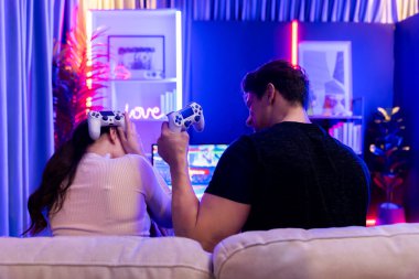 Kazanan adam video oyununda kadın kaybedenin yanında dövüşüyor. Televizyonda, stüdyo odasındaki kırmızı mavi ampulde joysticklerle oynayan bir çift. Varsayım.