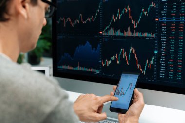 Akıllı borsa yatırımcıları ekranda akıllı telefon ile piyasa borsasını işaret ederek dizüstü bilgisayarın yanı sıra en yüksek dinamik yatırım oranını göstererek, modern işyerindeki veri planlamasına odaklanıyorlar. Bireysel.