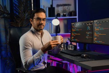 Bilgisayar ekranındaki yazılım geliştirme kodlarında kahve fincanı tutan akıllı bilişim geliştiricisi profili. Program güncellemesi internet sitesi verilerini neon ışığı siber ofisinde sunuyor. Tahmin et..