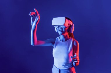 Siberpunk neon ışığı altında duran zeki kadın metaevrene bağlı VR kulaklık takıyor, gelecekçi siber uzay topluluğu teknolojisi. Zarif bir kadın parmak ucu kullanarak sanal bir obje oluşturur. Halüsinasyon.