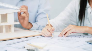 Profesyonel mühendis ev modelini tartartarken, yetenekli tasarımcı da planına yazar. Birlikte çalışmak, işbirliği, işbirliği. Yaratıcı tasarım ve takım çalışması konsepti. - Yakın çekim. Tertemiz.