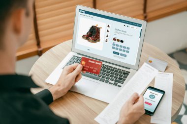 Genç adam internet bankacılığı için kredi kartlı dizüstü bilgisayar kullanıyor. İnternet üzerinden alışveriş yapıyor. Banka kartıyla modern ve kullanışlı online satın alma. Açılıyor