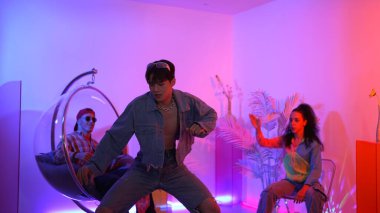 Çok kültürlü bir arkadaş kürsüde otururken Asyalı yetenekli bir dansçı modern müziğe geçiyor. Profesyonel dansçı, hipster takımı tezahürat yaparken ve desteklerken enerjik adımlar atıyor. Mutluluk.