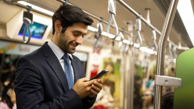 Trende insanlarla çevrili dururken telefona bakan profesyonel bir iş adamı. Kafkas proje yöneticisi e-postaları kontrol ediyor, arka planı bulanık pazarlama stratejisi planlıyor. Sevinçli..