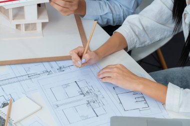 Profesyonel erkek mühendis ev modelini cetvel kullanarak ölçerken güzel bir iş arkadaşı da plan üzerinde yazarak birlikte çalışıyor. Yaratıcı tasarım ve takım çalışması. - Yakın çekim. Tertemiz..