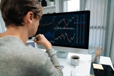 Bilgisayar ve dizüstü bilgisayarı kullanarak, çalışma masasındaki dinamik artırılmış borsa grafiğinin en yüksek kar değerini araştıran bir tüccar, modern ofisteki ekrandaki döviz kuru değerini analiz ediyor. Bireysel.