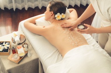 Lüks spa salonlarında sıcak mum ışığında cilt bakımı yaptıran kadın müşteri. Sağlık Spa vücut fırçasında tuz temizleme güzellik tedavisi. Sessiz.