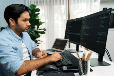 Akıllı IT geliştiricisi laptop ve iki pc ekranda kodlanan kağıtlar üzerine veri notları yazarak modern ofiste uygulama programı güncelleme sürüm sistemi yaratıyor. Tahmin et..