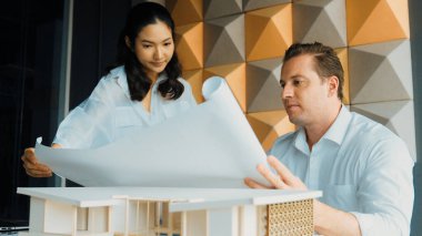 Mimar mühendis takım tasarımı portresi ve proje planı kullanarak ev hakkında tartışmak. Proje yöneticisi, ev inşaatını mimari modeli masaya yerleştirilmiş mühendislere açıklıyor. Yönlendirici.