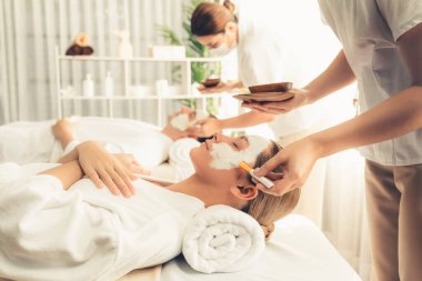 Kaplıca salonunun sakin atmosferi, modern gün ışığında lüks yüz kremi masajıyla gençleşmeye hevesli çiftler. Yüz bakımı ve güzellik konsepti. Sessiz.