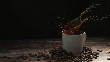 Kahve fincanının içine düşen buz tabakası ve siyah arkaplanla sıçrayan çok yavaş bir çekim. Etrafı kahve çekirdeği yığınıyla çevrili olan espresso 'nun içine şeker damlacıklarını kapatın. Hareket atışı. Geliştirilebilir.