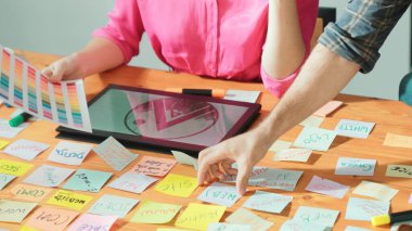 Yapışkan notlar ve tablet görüntülü grafik tasarımı ile toplantı masasındaki tablet görüntüleme logosunu gösteren akıllı yönetici elini kapat. İş ekibi birlikte çalışıyor ve fikir hakkında konuşuyor. Sempozyum.