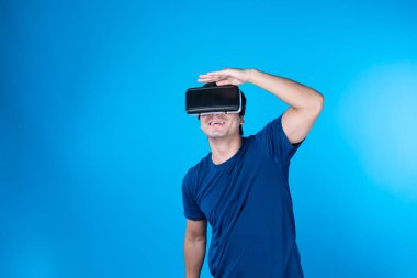 VR gözlük takan akıllı bir oyuncu golf sahası hologramı, dijital fütüristik teknolojiyi metaevren dünyasına bağlayan mavi arka plan ekranını izole etti. Entrika.